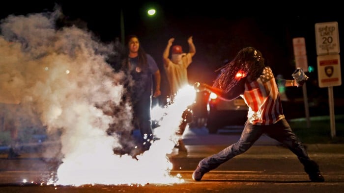 Edward Crawford returns a tear gas canister fired by police  who were trying to disperse protesters in Fergusons