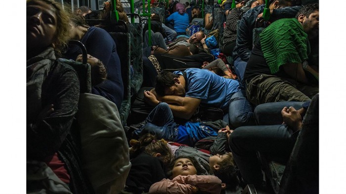 Ahmad Majid, en camiseta azul en el centro, duerme en un piso del autobús con sus hijos, su hermano Farid Majid, en suéter verde a la derecha, y otros miembros de su familia y de otros refugiados, después de salir de Budapest. Cientos de miles de refugiados, en su mayoría procedentes de Afganistán. Foto: Mauricio Lima/ The New York Times