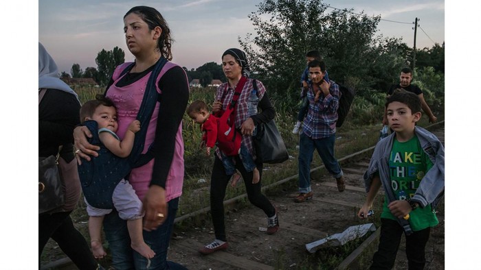Roujin Sheikho, a la izquierda, de Siria, lleva a su hija y Widad Nabih, a la derecha, lleva a su hijo, caminan con otros refugiados sirios por las vías del ferrocarril antes de cruzar a Hungría desde Horgoš, Serbia. Foto: Mauricio Lima/ The New York Times