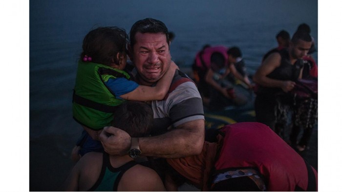 Laith Majid de Irak,celebra la llegada de sus hijos a Kos, Grecia, en un bote de goma frágil. Foto: Daniel Etter/ The New York Times