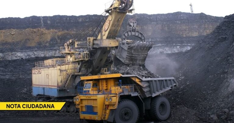 Mining site scene with a massive excavator loading coal into a large dump truck at a coal quarry, with a yellow 'NOTA CIUDADANA' banner in the corner. - La falta de políticas energéticas claras y eficientes frena a Colombia como potencia energética