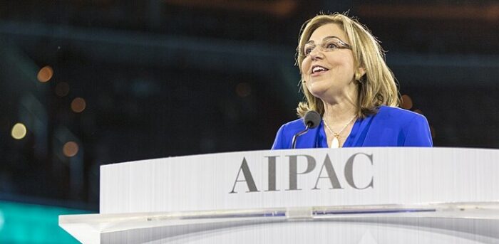 Woman in a blue blazer speaks at a podium with AIPAC logo. - Un senador de origen colombiano y otros demócratas quieren frenar el lobby judío en el Congreso