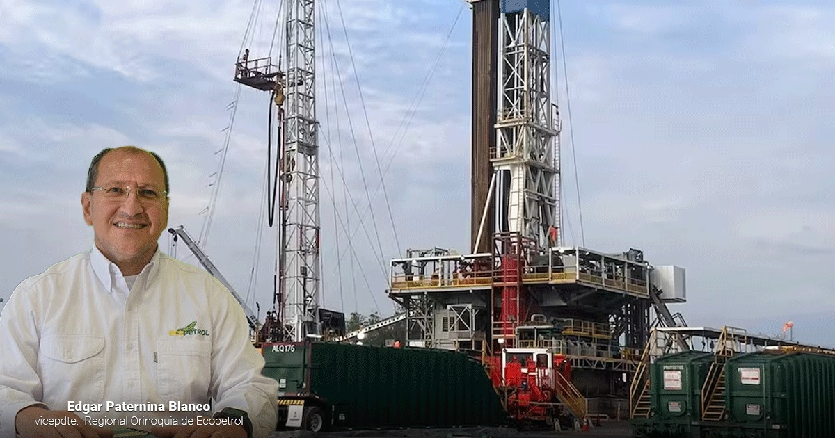 Man in a cream work shirt stands in front of a large oil/gas drilling rig during operation, on a paved site with equipment nearby. - Un pozo nuevo de Ecopetrol en los Llanos sorprendió con 3mil barriles diarios