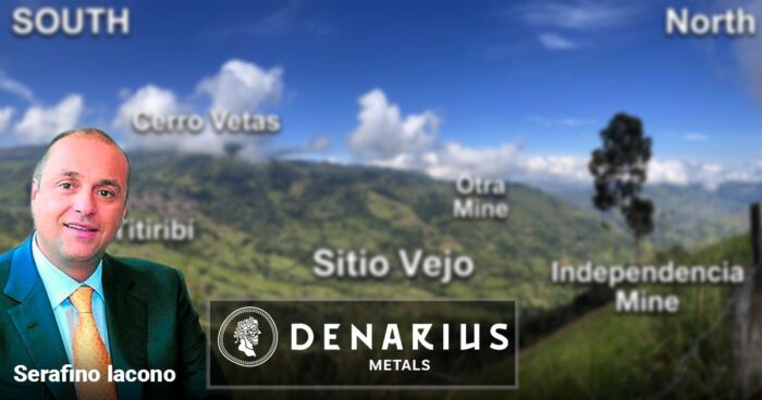 Portrait of a man in a blue suit and orange tie on the left, with a blurred hillside map showing mining sites and North/South labels, plus a Denarius Metals logo overlay. - La última aventura de Serafino Iacono: sacarle más oro a El Zancudo