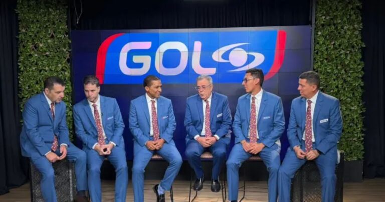 Six men in matching blue suits and maroon patterned ties sit on stools in front of a large GO L logo backdrop, suggesting a panel or interview setting. - El equipo de lujo que Gol Caracol armó para el Mundial 2026 y ser el rey del rating