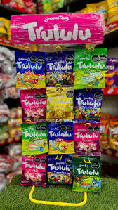 Display rack of Trululu gummy candies in assorted flavors with pink, blue, yellow, and green bags on a store stand. - La repostería Deli le ganó a una multinacional China