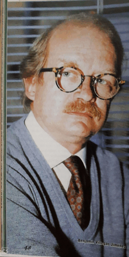 Portrait of a middle-aged man with round tortoiseshell glasses, mustache, wearing a blue striped suit and patterned tie. - Los lujosos libros de Villegas Editores que ahora podrán estar al alcance de cualquier bolsillo