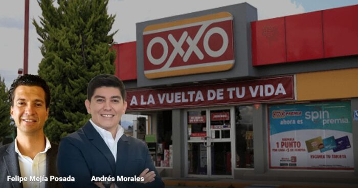 Two men in suits stand in front of an OXXO convenience store with a red banner reading 'A LA VUELTA DE TU VIDA'. - Las2orillas.co: Historias, voces y noticias de Colombia