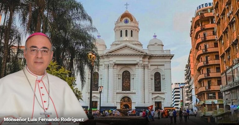Monsignor Luis Fernando Rodríguez in white clerical robes with a pink zucchetto in the foreground; a white cathedral and city street with people behind him. - Las2orillas.co: Historias, voces y noticias de Colombia