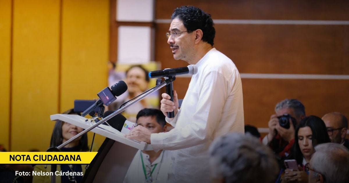 Man in a white shirt speaks at a podium with a microphone, surrounded by reporters and cameras; a yellow 'NOTA CIUDADANA' banner and photo credit 'Foto: Nelson Cárdenas' appear at the bottom left. - Los cuatro errores de Iván Cepeda que revivieron a la derecha y lo hicieron tambalear en la primera vuelta