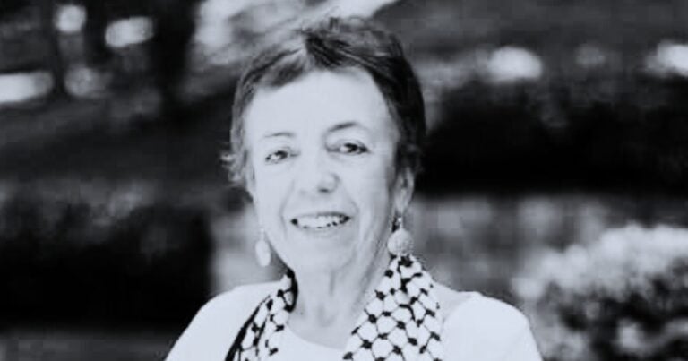 Smiling woman with short hair wearing a patterned scarf and drop earrings, outdoors in a garden. (informative portrait) - La apuesta por la vida y contra el fascismo continúa