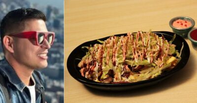 Smiling man in bright red sunglasses on a city rooftop, next to a plate of loaded nachos with lettuce and drizzled sauces. - Barranquilla vivirá un festivo dedicado a un plato insignia de la comida rápida