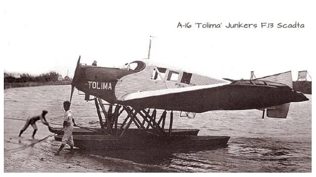 Cómo Avianca, la aerolínea más antigua de América ha sobrevivido a quiebras, guerras y atentados Junkers F13 airplane named Tolima mounted on a pontoon float on a river, with children playing in the water nearby. - Cómo Avianca, la aerolínea más antigua de América ha sobrevivido a quiebras, guerras y atentados