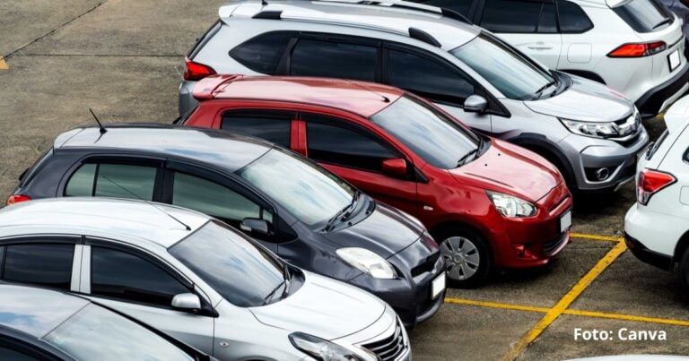 Aerial view of a parking lot with several cars parked diagonally; red compact car in the center surrounded by white and gray vehicles, yellow parking lines visible. - Las2orillas.co: Historias, voces y noticias de Colombia
