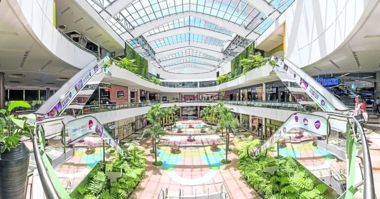 Bright multi-level shopping mall atrium with escalators, glass ceiling, and tropical plants to create a sunny, open feel. - Las2orillas.co: Historias, voces y noticias de Colombia