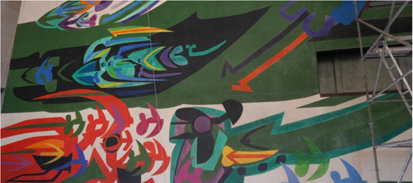 Colorful abstract graffiti mural on a building wall with green, red, blue, and purple shapes and a scaffold on the right. - Tres constructoras que lograron levantar el Museo de Arte Moderno de Barranquilla