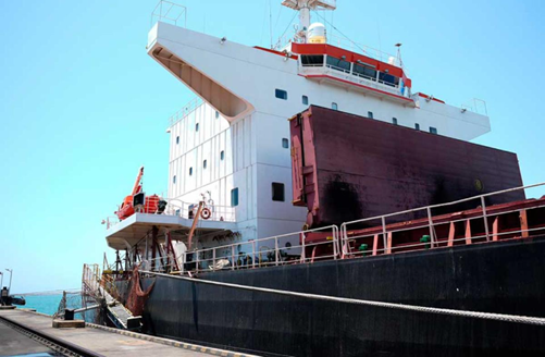 Large cargo ship docked at a pier, white superstructure with a red upper deck and a dark hull, mooring lines along the side. - Con el sector privado detrás Ciénaga tendrá puerto moderno y moverá la carga del tren