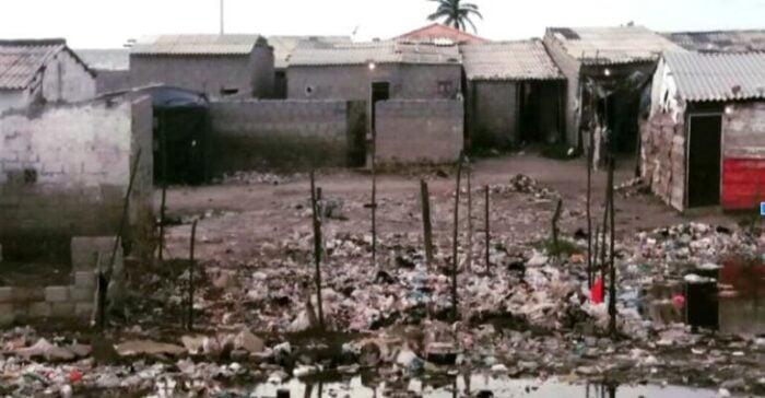 A waste-filled yard with muddy water, scattered trash, and simple concrete shacks in a poor neighborhood dockside area. - Las guardianas de las aves que le están cambiando la cara a Tasajera con turismo y emprendimientos 