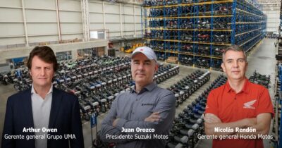 Three executives in a motorcycle warehouse: Arthur Owen, Juan Orozco, and Nicolás Rendón, with rows of motorcycles behind them. - Tres marcas asiáticas desplazaron a AKT del empresario paisa Manuel Santiago Mejía