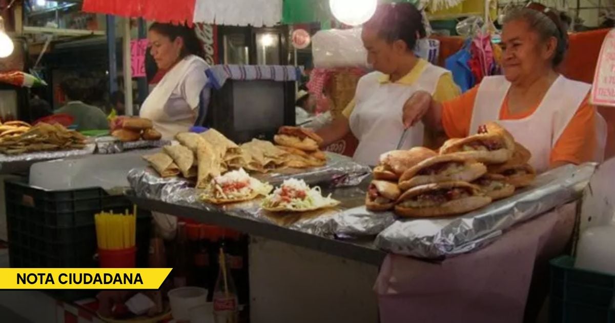 Three vendors work at a busy street market stall selling sandwiches and fried snacks, with piles of tortas on a foil-covered counter and colorful décor above. - La sorpresiva bonanza económica que México le arrebató a EE. UU. con el Mundial