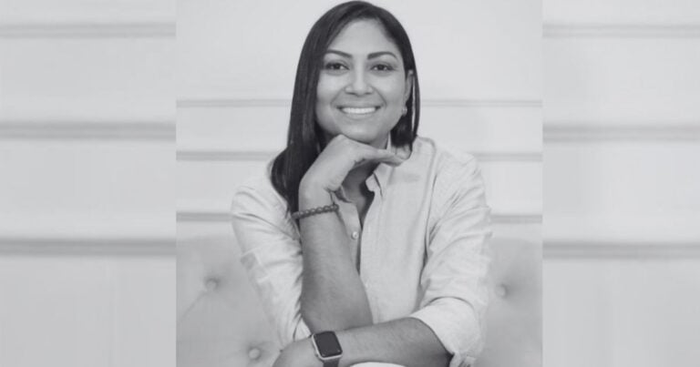 Smiling woman with dark hair in a light button-down shirt rests her chin on her hand on a tufted sofa (black-and-white portrait). - La Guajira no necesita más diagnóstico. Necesita volver a sembrar