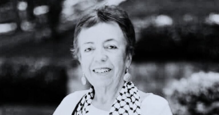 Smiling woman with short hair wearing a checkered scarf outdoors in a garden or park setting. - El discurso del presidente y el segundo grito de independencia