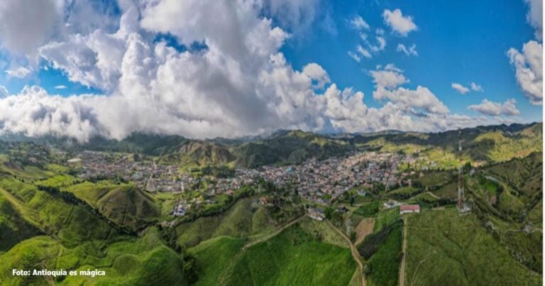 Las2orillas.co: Historias, voces y noticias de Colombia Panorámica de un valle verde con un pueblo rodeado de cerros y un cielo azul con nubes; se ve la frase 'Foto: Antioquia es mágica' en la esquina. - Las2orillas.co: Historias, voces y noticias de Colombia