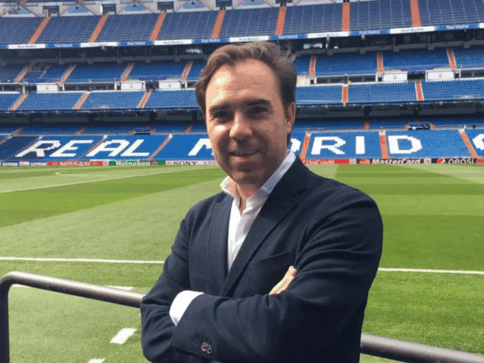 El francés dueño Caracol Radio quiere sacarle una fortuna a Millonarios, el equipo bogotano que compró hace 15 años Man in a dark blazer posing with folded arms on a stadium railing, with a green pitch behind him. - El francés dueño Caracol Radio quiere sacarle una fortuna a Millonarios, el equipo bogotano que compró hace 15 años