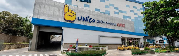 Exterior view of the UNICO Centro Comercial shopping center with a yellow thumbs-up logo, blue trim, and a car drop-off area - La empresa china que perdió el pulso con los centros comerciales tipo outlet