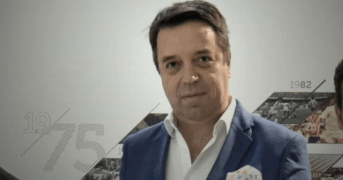 El francés dueño Caracol Radio quiere sacarle una fortuna a Millonarios, el equipo bogotano que compró hace 15 años Man in a blue blazer and white shirt posing for a photo in front of a timeline display with years like 1975 and 1982 in the background - El francés dueño Caracol Radio quiere sacarle una fortuna a Millonarios, el equipo bogotano que compró hace 15 años