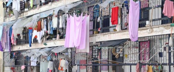 Edificio de varios pisos con ropa colgada y balcones, ropa colorida secándose al aire libre.