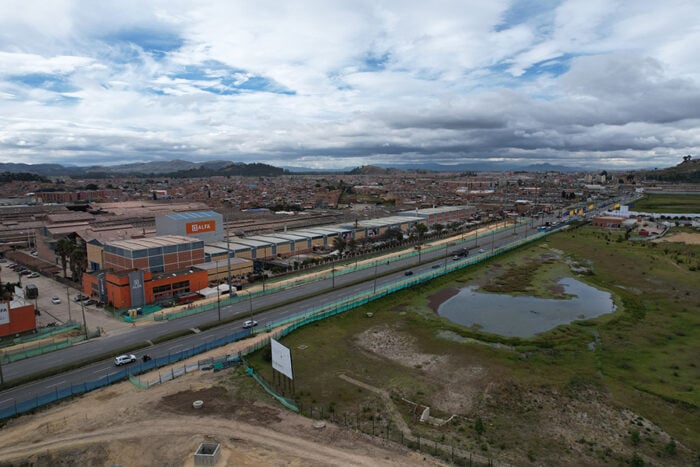 Los Lozada aliados a una empresa francesa se quedaron con la billonaria licitación para los buses de Transmilenio Aerial view of a commercial district with orange and gray industrial buildings, a wide road, and a small pond on a grassy area to the right. - Los Lozada aliados a una empresa francesa se quedaron con la billonaria licitación para los buses de Transmilenio