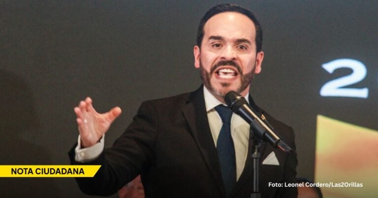 Man in a dark suit and blue tie speaks into a microphone on stage, with a yellow 'NOTA CIUDADANA' banner at the lower left. - Las primeras dos semanas del indolente gobierno de Abelardo de la Espriella