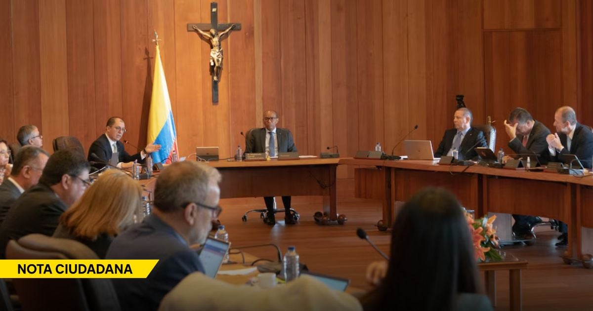 Government meeting in a wood-paneled room with officials around a long conference table; a crucifix and a Colombian flag on the wall. - El traslado de procesos de corrupción a juzgados gringos pone a prueba la soberanía de la justicia colombiana