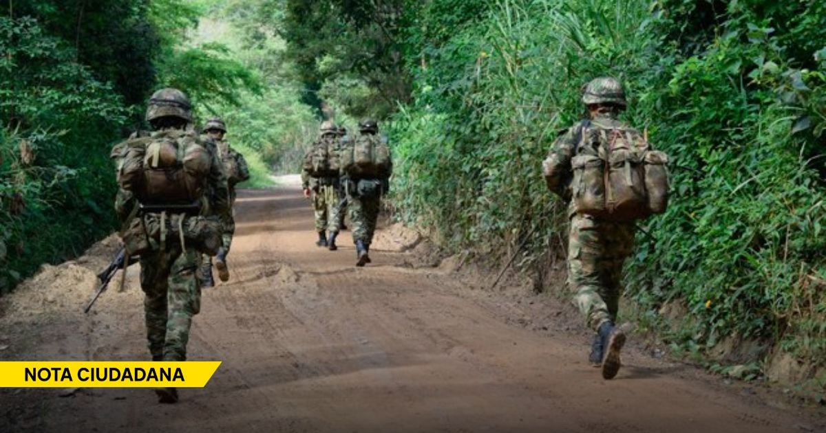 Soldiers in camouflage marching along a dirt road through dense jungle, carrying packs; yellow NOTA CIUDADANA banner at bottom left. - La falta de coordinación con Venezuela le ata las manos al Ejército en el Catatumbo