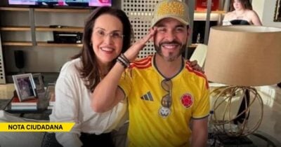Woman with glasses and a man in a yellow Colombia soccer jersey pose together on a couch, smiling at the camera. - Las2orillas.co: Historias, voces y noticias de Colombia