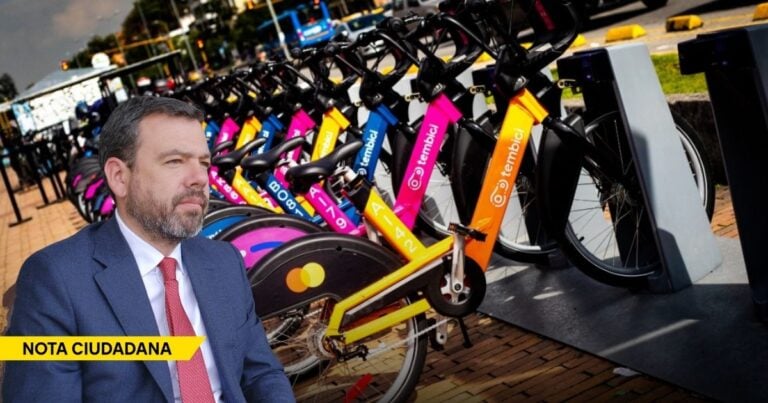 Man in a blue suit sits in the foreground while a line of colorful shared bicycles stands behind him, with a yellow 'NOTA CIUDADANA' banner in the corner. - La alcaldía de Galán saca pecho con Tembici, una empresa que cobra por bicicletas eléctricas que no existen