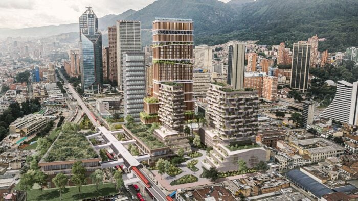 Aerial view of a modern city with tall, terraced buildings and a red elevated train line cutting through the urban core. - Después de 13 años, el ambicioso Plan de Galán para el centro vuelve a ponerse en marcha