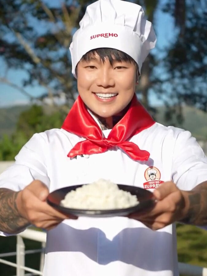 El influencer extranjero radicado en Colombia que es el número uno con 15 millones de seguidores en Instagram y TikTok Smiling chef in a white uniform and hat presents a bowl of steamed rice outdoors, held toward the camera. - El influencer extranjero radicado en Colombia que es el número uno con 15 millones de seguidores en Instagram y TikTok