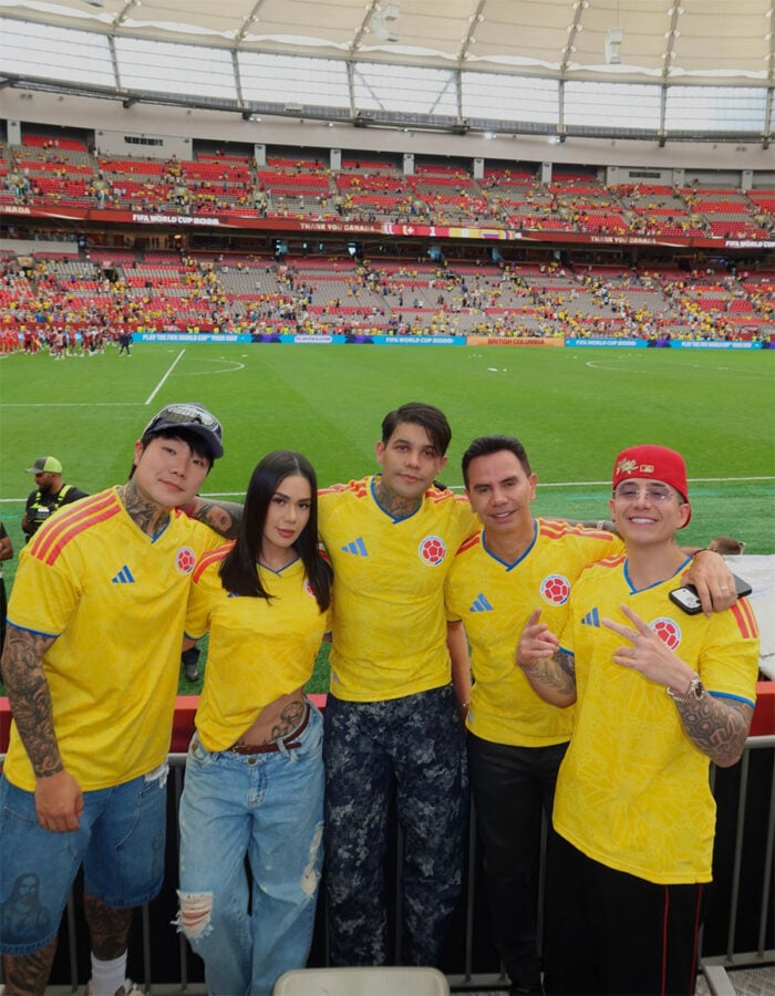 El influencer extranjero radicado en Colombia que es el número uno con 15 millones de seguidores en Instagram y TikTok Five people in yellow Colombia jerseys pose for a photo at a soccer stadium, with a green field and stands in the background. - El influencer extranjero radicado en Colombia que es el número uno con 15 millones de seguidores en Instagram y TikTok