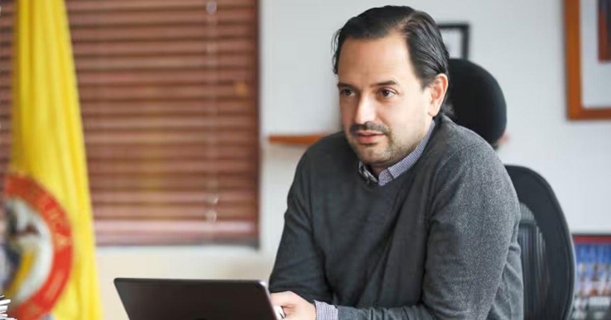 Man in a gray sweater sits at a desk with a laptop in an office setting with blinds in the background. - Primer triunfo diplomático De la Espriella: Diego Mesa a uno de los fondos ambientales más importantes del mundo