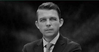 Black-and-white headshot of a man in a suit and tie, looking at the camera. - El camino es el correcto