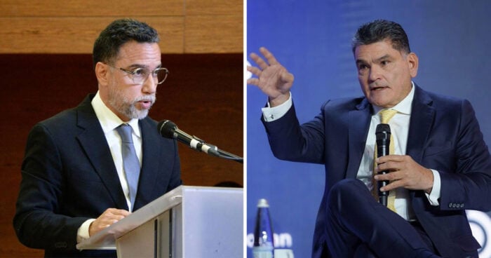 Por qué tambalea el contrato de pasaportes que Petro firmó con los portugueses y la Imprenta Nacional Two men in dark suits speak on stage at a formal event; left at a podium with a microphone, right gesturing while holding a handheld mic against a blue backdrop. - Por qué tambalea el contrato de pasaportes que Petro firmó con los portugueses y la Imprenta Nacional