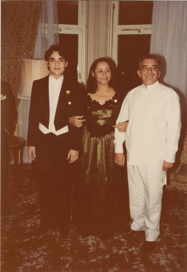Adiós a la casa de Gabo donde recibió la noticia del Nobel y murieron él y Mercedes en Ciudad de México Three people pose for a formal photo: a young man in a black tuxedo, a woman in a dark floral dress, and a man in a white chef’s uniform standing in a room with patterned carpet. - Adiós a la casa de Gabo donde recibió la noticia del Nobel y murieron él y Mercedes en Ciudad de México