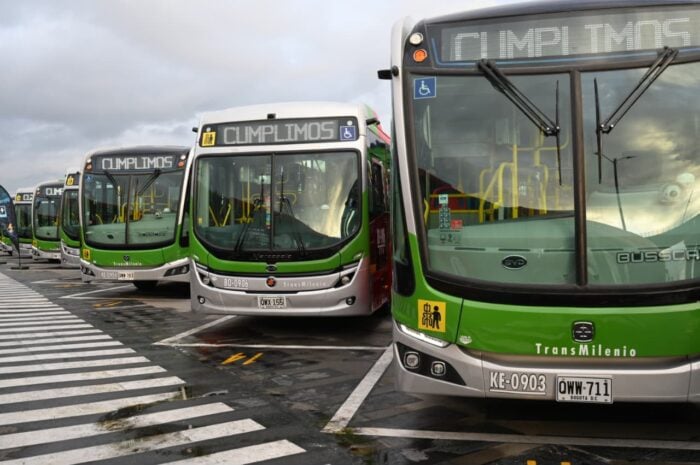 Los chinos en asocio con fabricantes de carrocerías caleños y brasileños hicieron 50 buses duales de Transmilenio Several green and white TransMilenio buses lined up at a bus terminal, with a zebra crossing in the foreground. - Los chinos en asocio con fabricantes de carrocerías caleños y brasileños hicieron 50 buses duales de Transmilenio