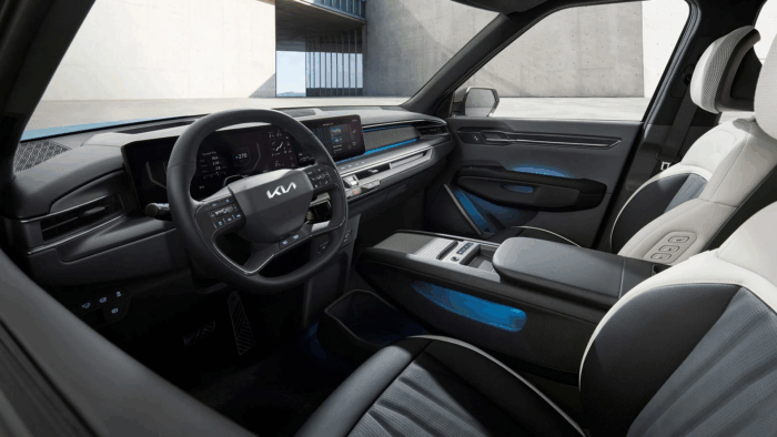 La camioneta eléctrica de Kia que parece sacada del futuro: seis pasajeros, potente y con casi 500 km de autonomía Front interior of a Kia SUV with a digital instrument cluster, large touchscreen, and blue ambient lighting. - La camioneta eléctrica de Kia que parece sacada del futuro: seis pasajeros, potente y con casi 500 km de autonomía