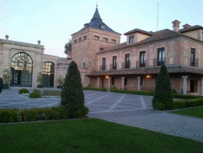 La opulenta vida del venezolano escogido de Trump para hacer los negocios de las petroleras gringas Brick villa with a tall central tower, arched glass doors, and a formal courtyard with trimmed evergreens and cobblestone paths. - La opulenta vida del venezolano escogido de Trump para hacer los negocios de las petroleras gringas