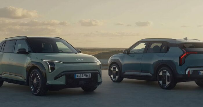 Kia se metió de lleno en los eléctricos con una camioneta que sorprende más cuando uno se pone al volante Two teal Kia electric SUVs parked on a sandy area at sunset, facing opposite directions with a calm horizon in the background. - Kia se metió de lleno en los eléctricos con una camioneta que sorprende más cuando uno se pone al volante