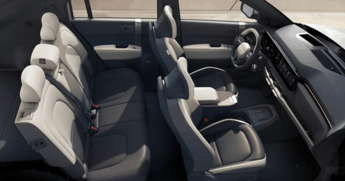Kia se metió de lleno en los eléctricos con una camioneta que sorprende más cuando uno se pone al volante Interior view of a modern SUV with two front seats and a second-row bench, light gray upholstery, and a dark dashboard. - Kia se metió de lleno en los eléctricos con una camioneta que sorprende más cuando uno se pone al volante