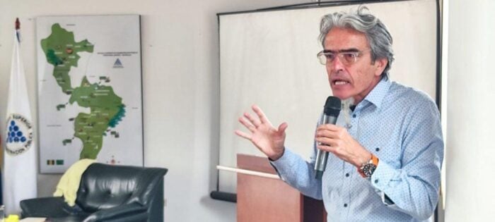 ¿Quiénes son los tres académicos con los que Petro se quería atornillar en la U. Nacional antes de dejar la Presidencia? A man in a light blue shirt speaks into a handheld microphone while gesturing during a presentation in an office setting with a map on the wall behind him. - ¿Quiénes son los tres académicos con los que Petro se quería atornillar en la U. Nacional antes de dejar la Presidencia?